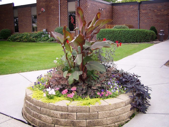 Round raised flower bed stands in center of a walking path
