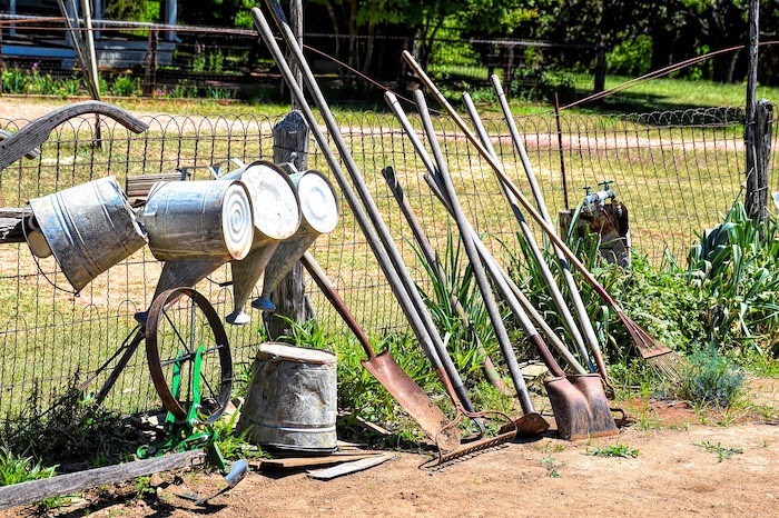 Gardening tools lean against a wire fence