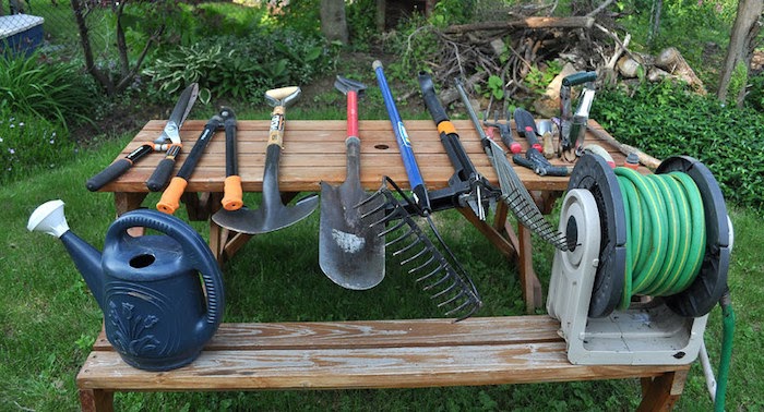 A set of garden tools spread out on a wooden picnic table