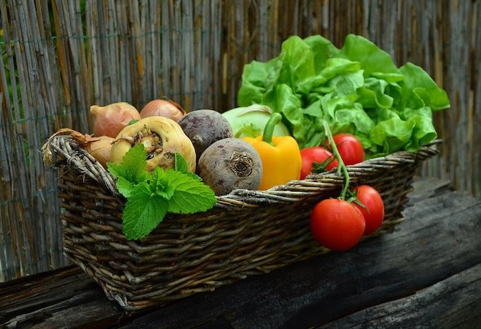 A basket of vegetables, including lettuce, tomatoes, and onions