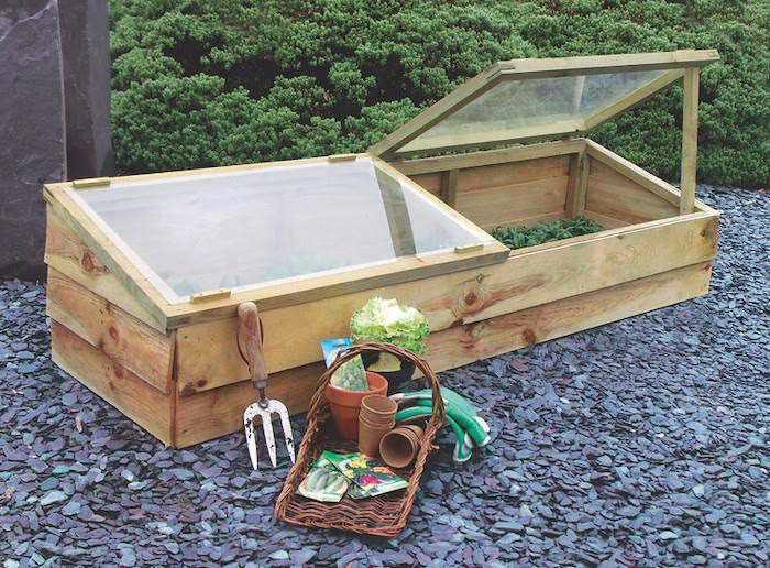Wooden cold frame sits on a gravel surface