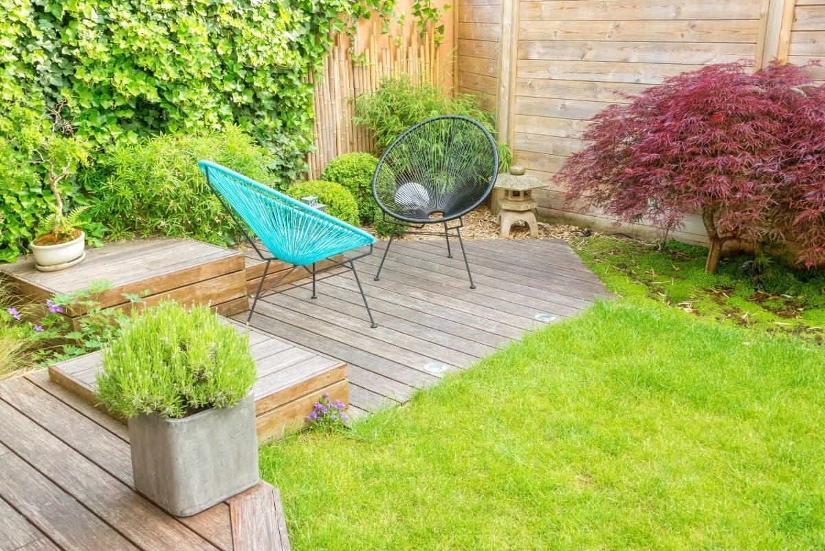 Two butterfly chairs on small patio with wooden flooring in urban garden