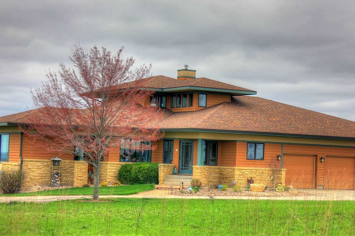 storm clouds over a large house with a green lawn