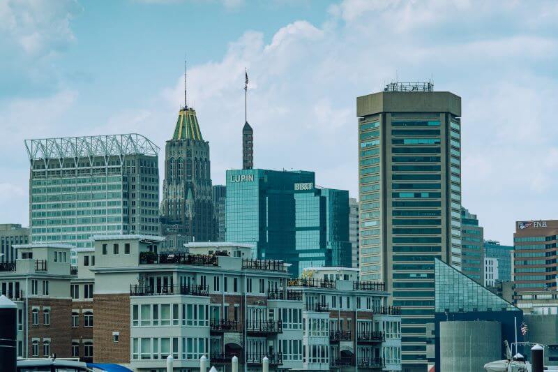 Skyscrapers and high-rise apartments stand tall in front of a big cloud in Baltimore.