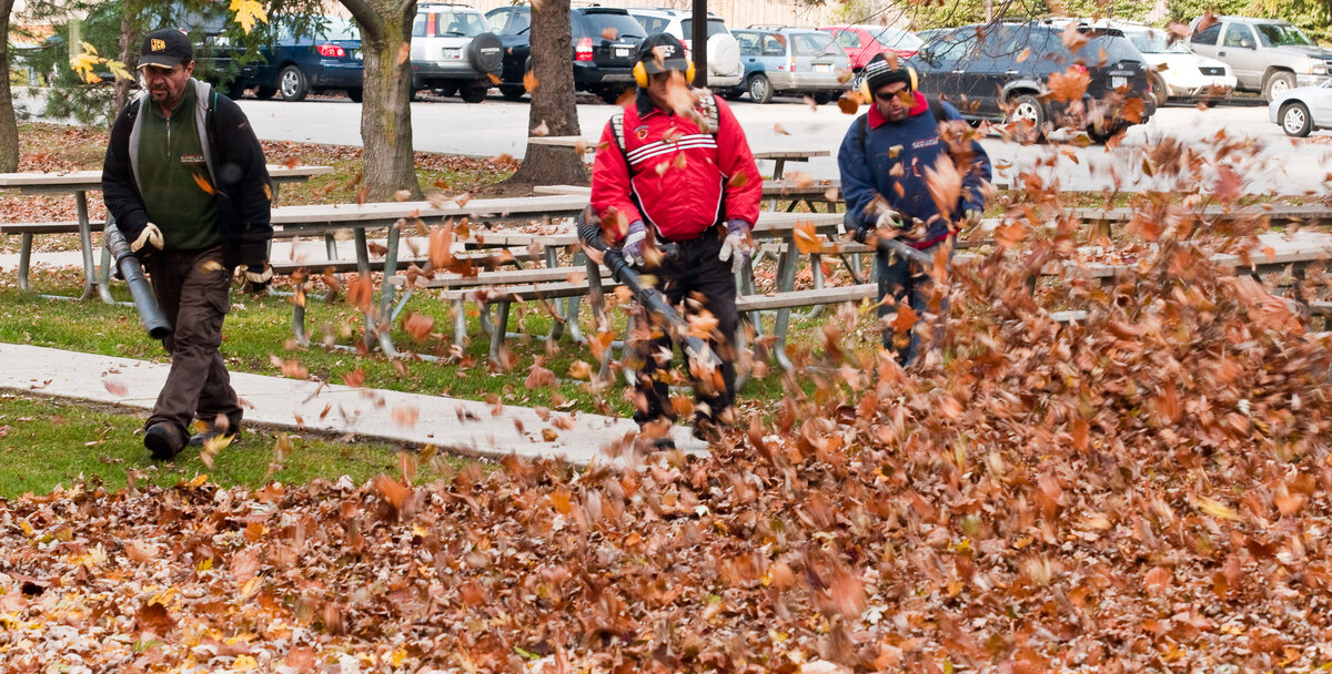 Three men blowing leaves with leaf blowers
