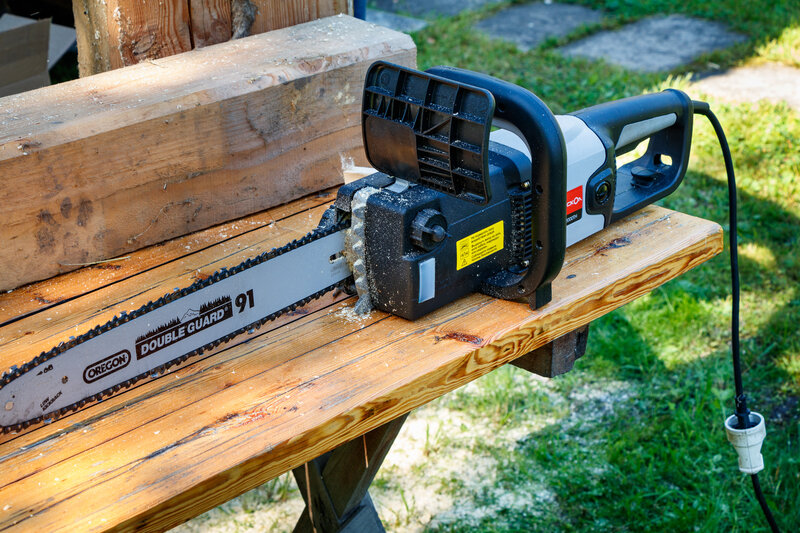 electric chainsaw resting on a wood workbench.