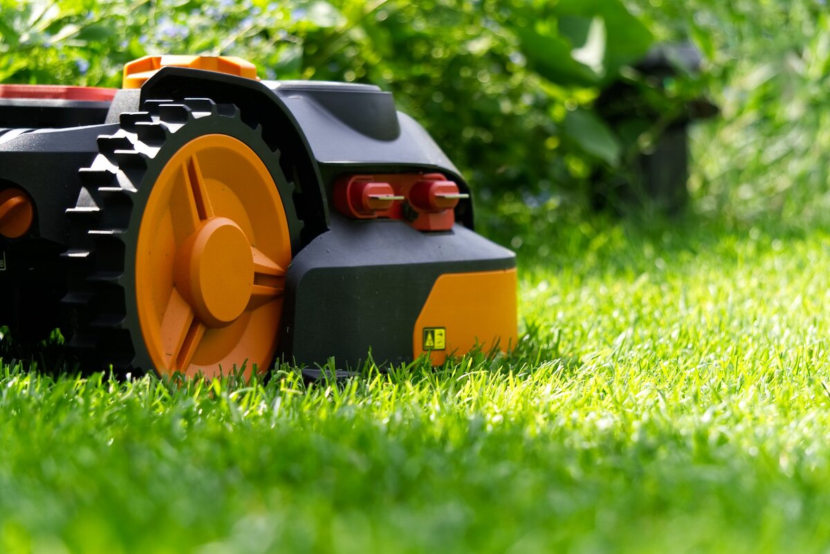 Side profile of an orange and black robot mower on a lawn