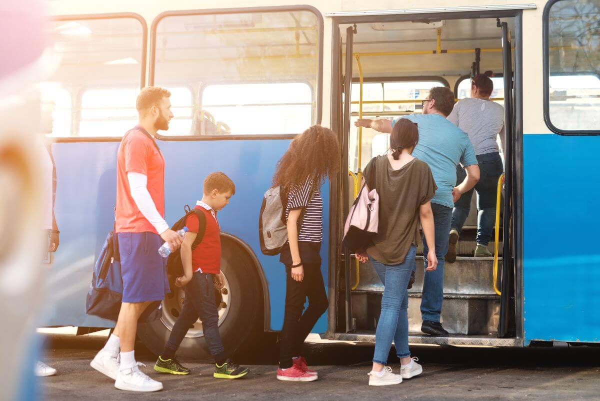 Group of commuters of varying ages and genders boards a public bus