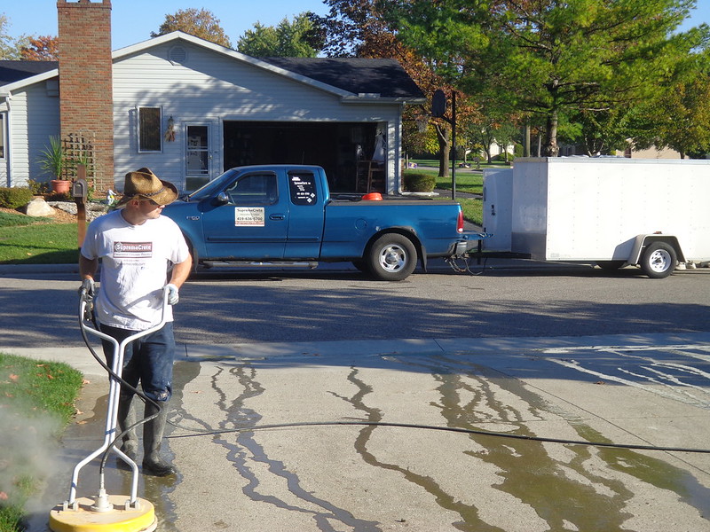 Worker cleaning a driveway with an industrial brush