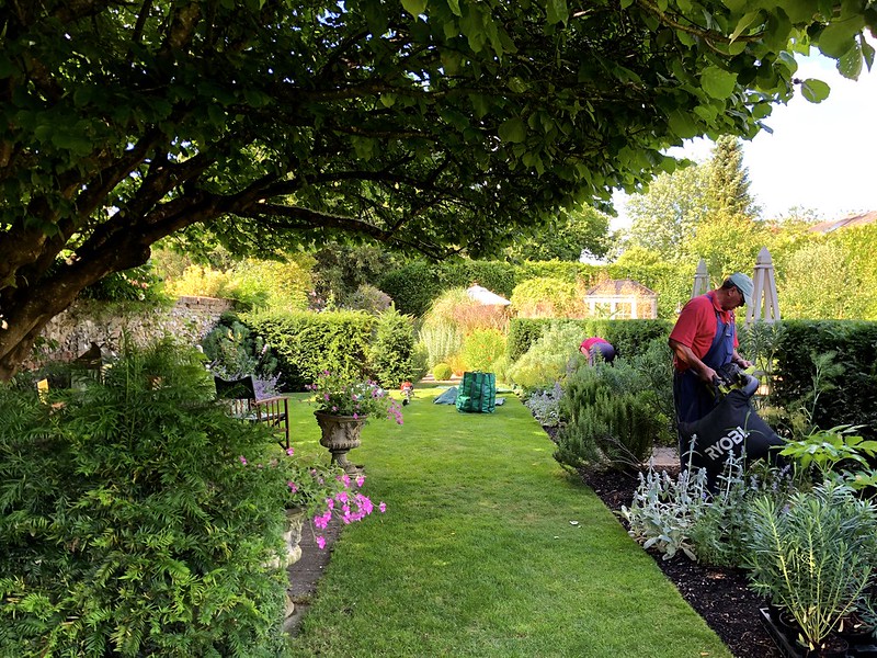 Worker gardening in a large, ornate garden