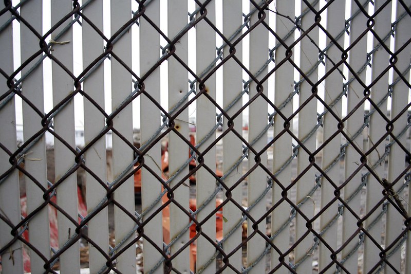 Close-up of a chain-link fence with white privacy slats within it