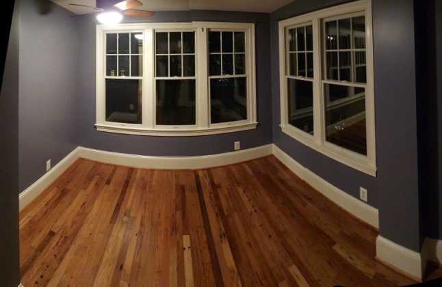 A room with wooden floor and white windows