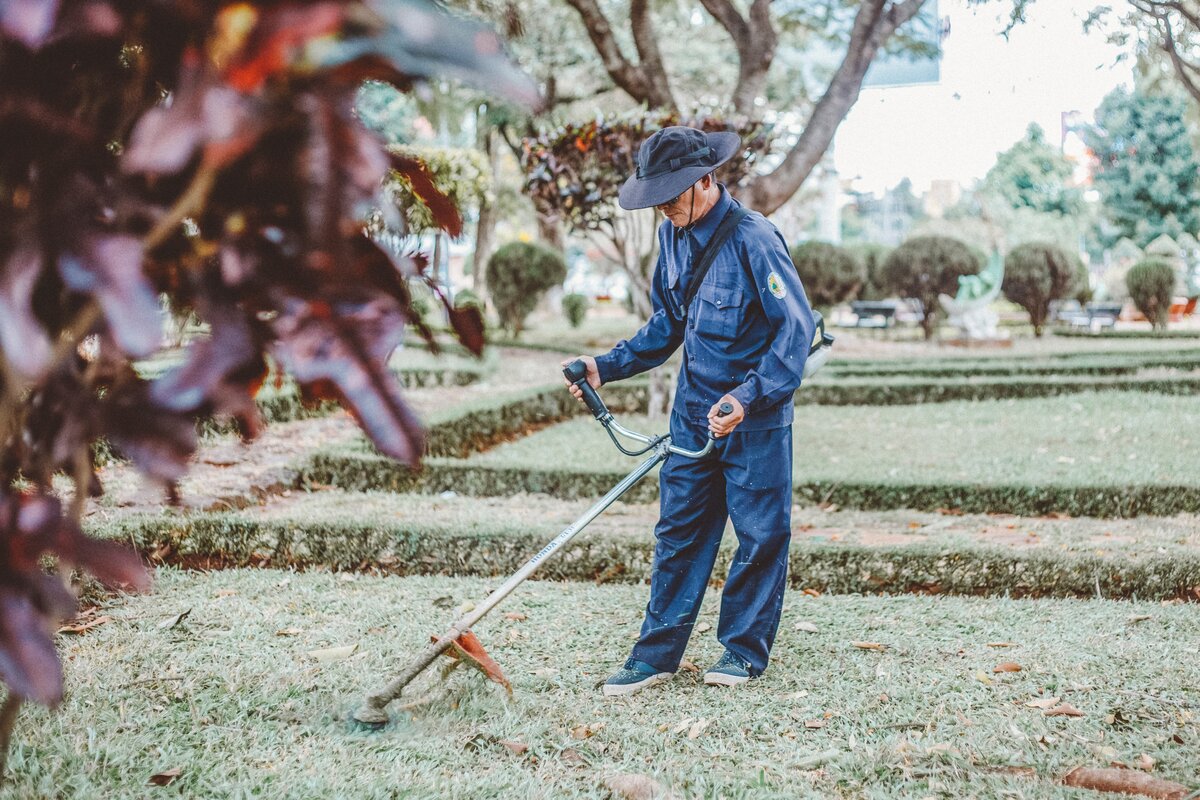 man working outdoors using string trimmer on a landscaping job