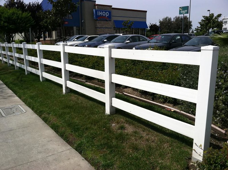 White vinyl fence showing the length down a sidewalk