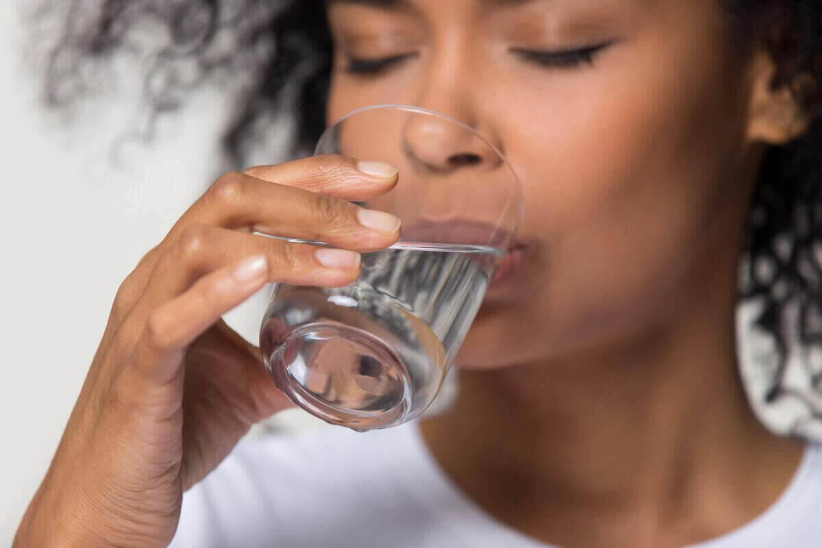 Multiethnic woman, early 30s, drinking a glass of water