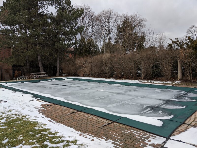 Swimming pool with a cover on it, and covered in snow