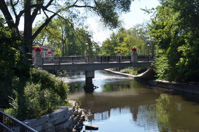 A shot of a bridge adorned with flowers over the DuPage River in Downtown Naperville, Illinois