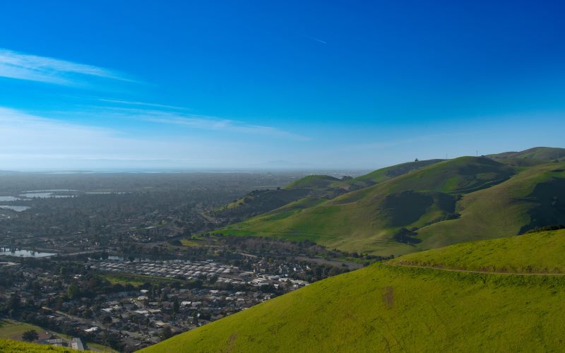 A view of a valley neighborhood on the left and hills on the right and foreground shot from Vargas Plateau Regional Park and Morrison Canyon Road in Fremont, California