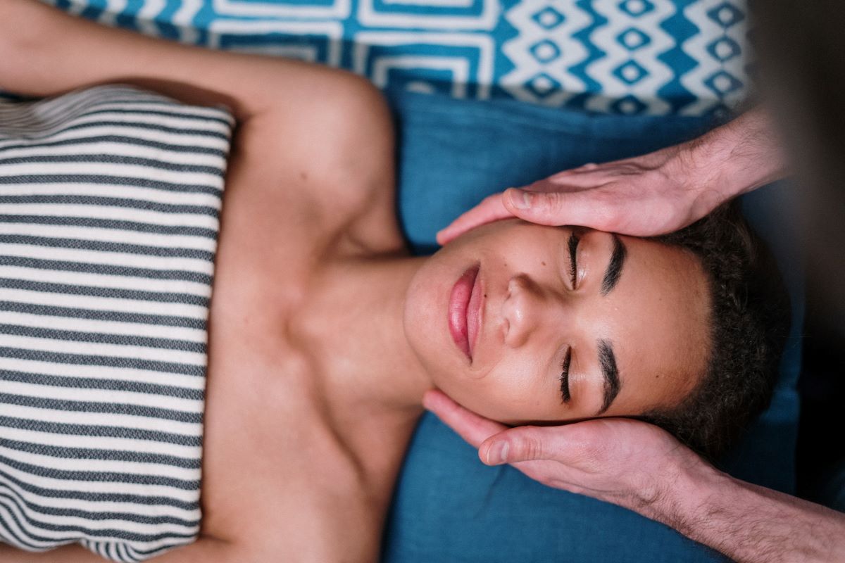 A woman smiles slightly, feeling relaxed as she receives a massage. Title: 2023's Most Relaxed Cities