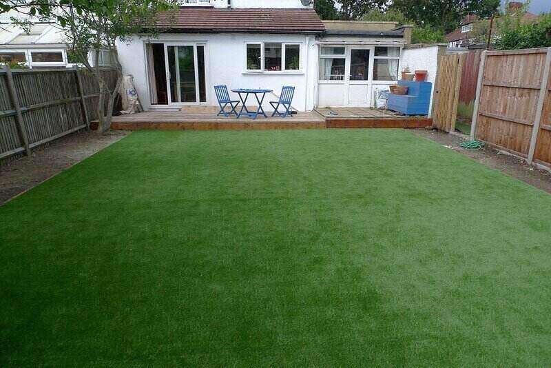 Backyard with artificial turf and a patio set on a deck