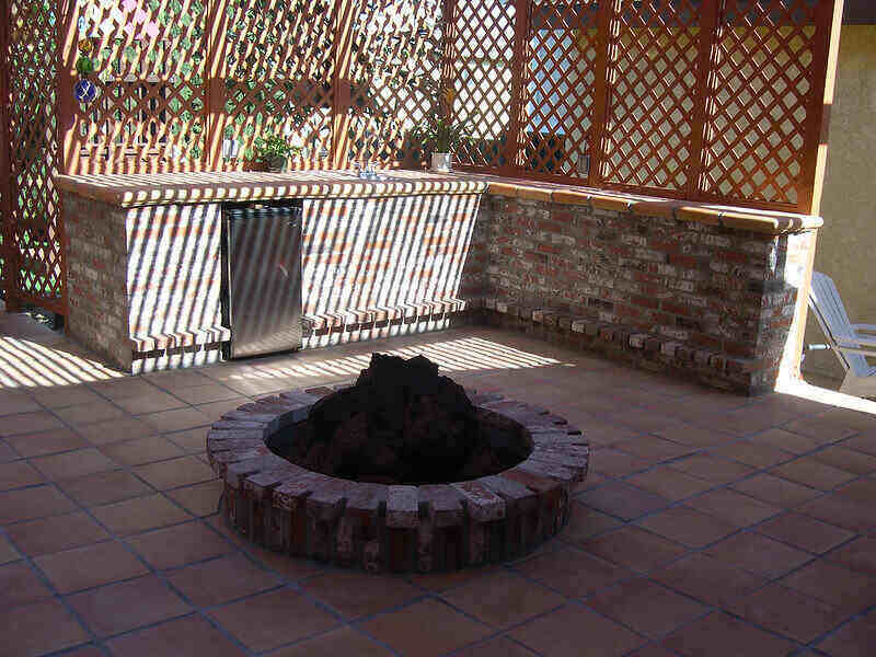 Shaded picture of an outdoor patio with a built-in kitchen and fire pit