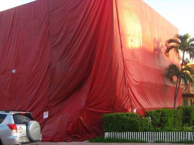 Carpa roja grande cubierta sobre una casa para exterminar plagas