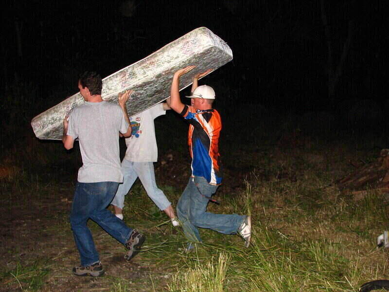 Three men carrying a mattress