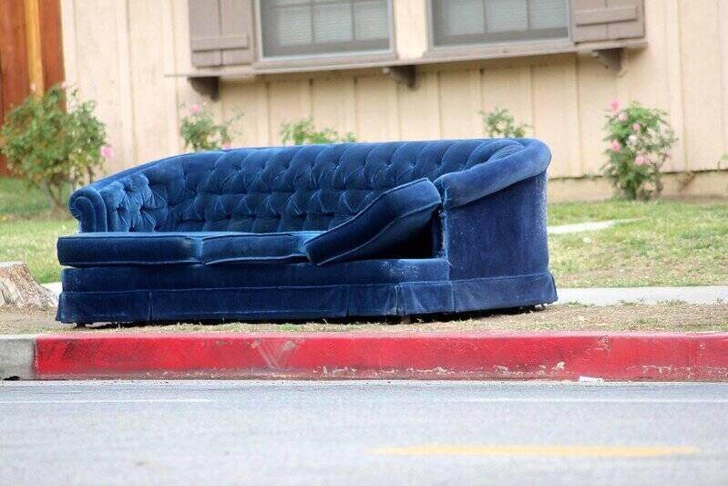 An abandoned blue velvet sofa on the curb
