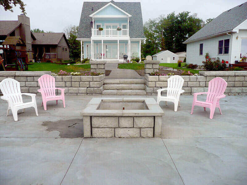 Stone firepit in a concrete patio with chairs around it