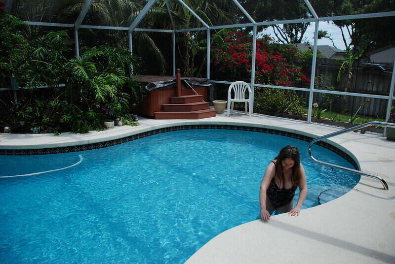 Woman getting out of a pool with an enclosure around the pool