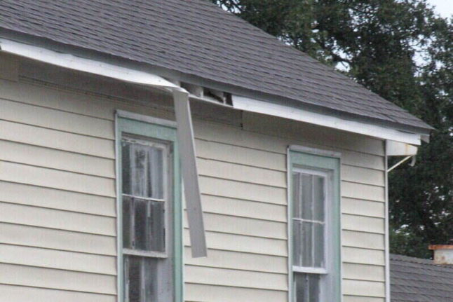 A loose gutter hanging from the edge of a roof