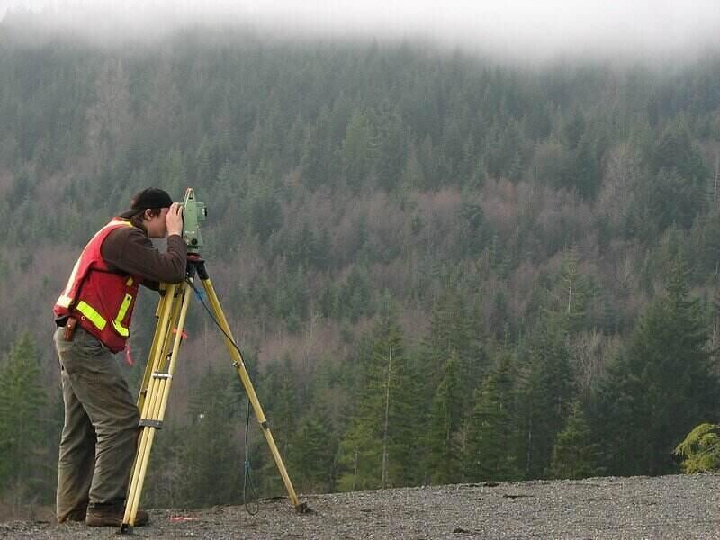 Worker conducting a land survey in a forested area