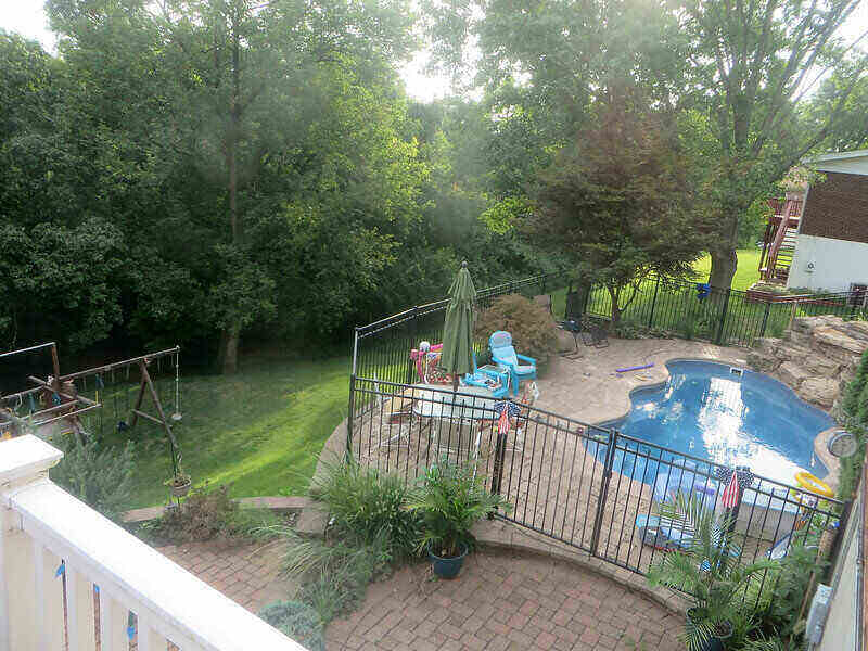 Shot over-head of a pool in a backyard, enclosed by a gate