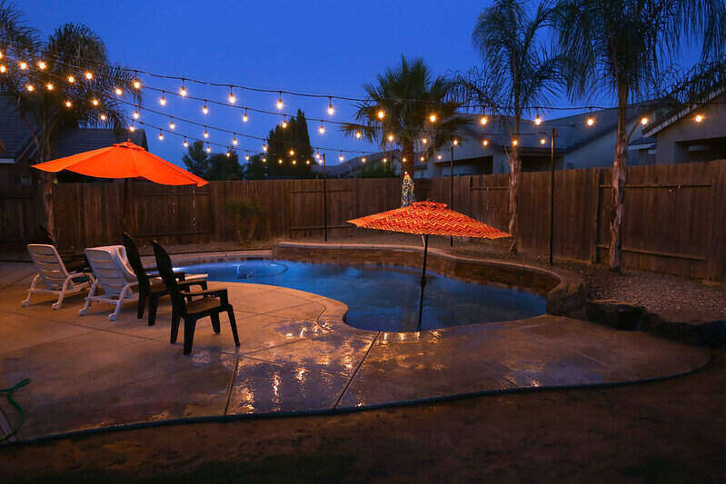 Lights strung over a pool at sunset