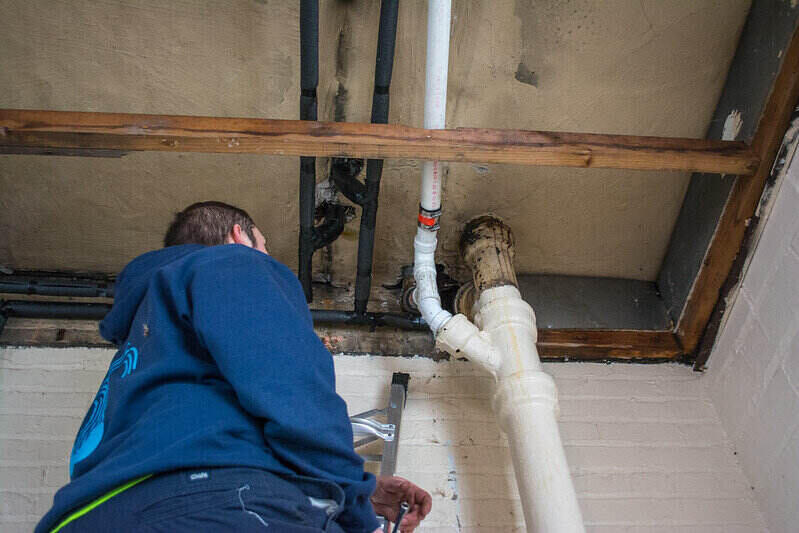 Worker fixing a pipe in the upper part of a ceiling