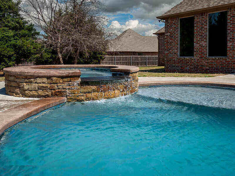 Stone hot tub connected to an in-ground pool