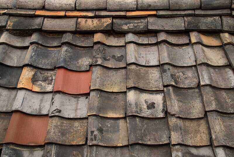 Close up of old roof tiles that are chipped and discolored