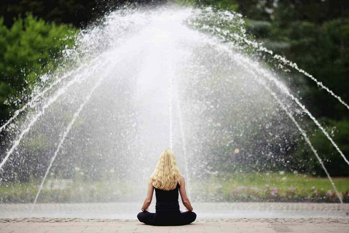Woman sitting in front of a fountain with her back to the camera