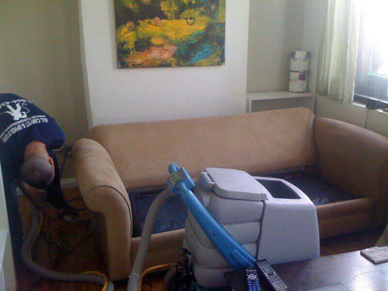 Man using a steam cleaner on a couch