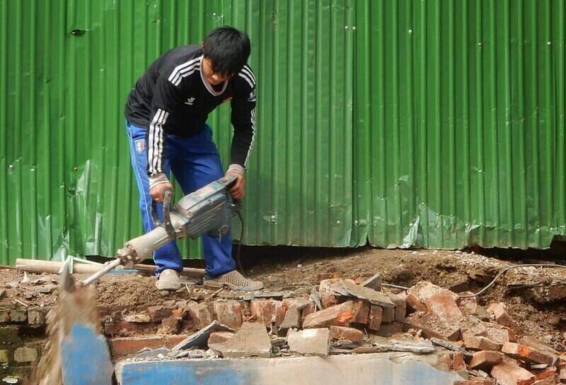 Worker using a jackhammer to break-up concrete