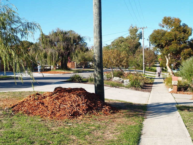 Large pile of mulch near a telephone pole