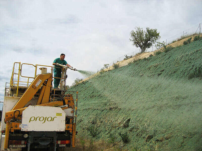 Workers hydroseeding the slope of a landscape