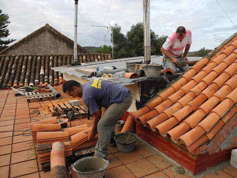 Two workers replacing tile roofing