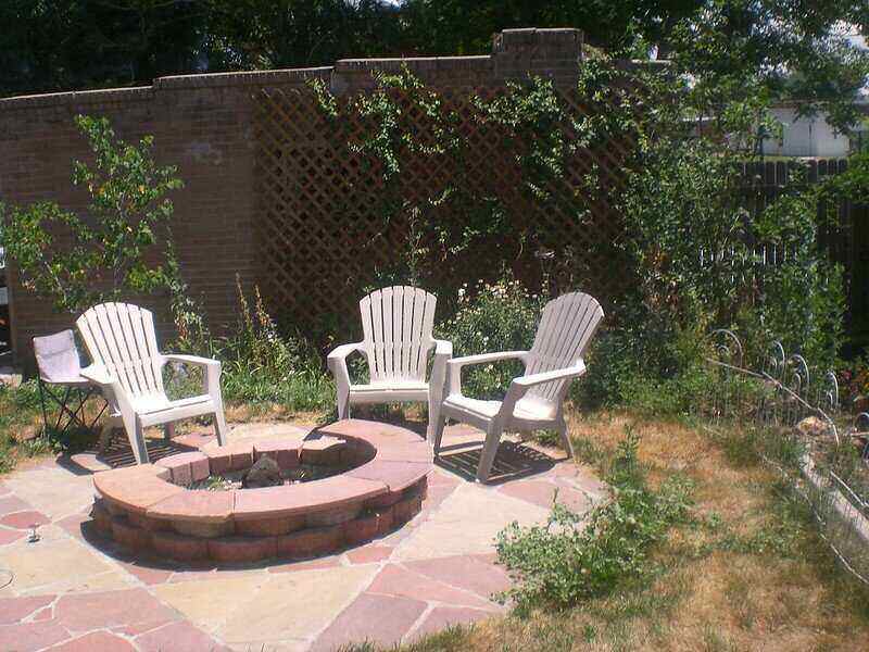 Chairs around a brick and concrete fire pit in the middle of a circular patio