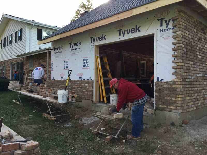 Workers putting brick veneer on a house