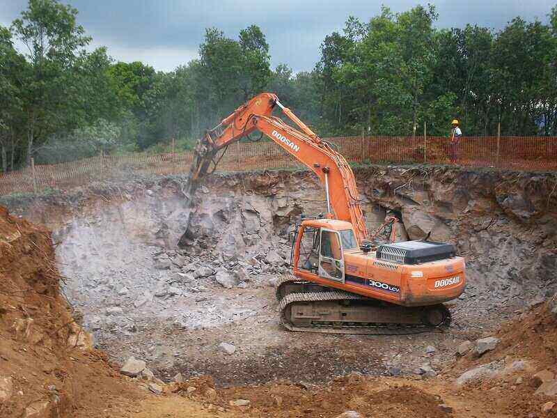 Backhoe in the center of a large hole, digging into it