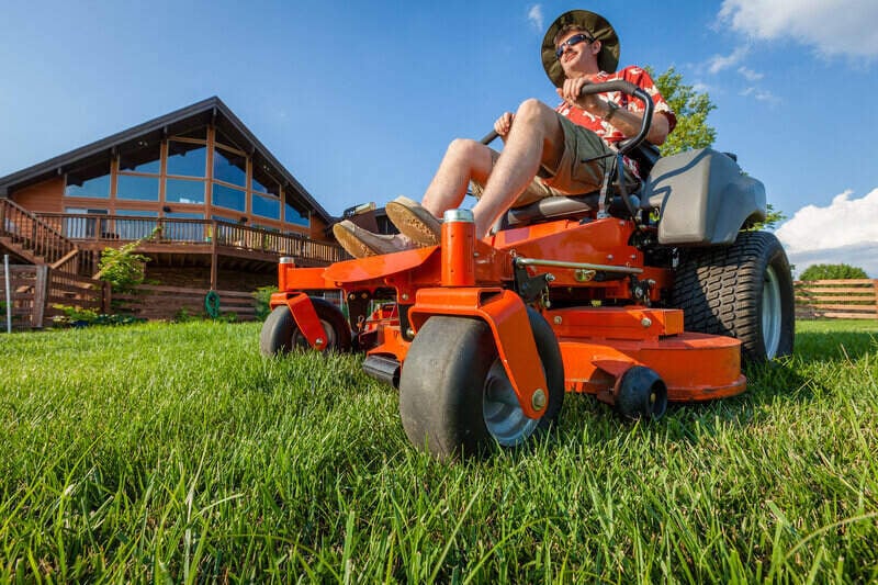 Man enjoying cutting his grass atop a zero turn riding lawn mower