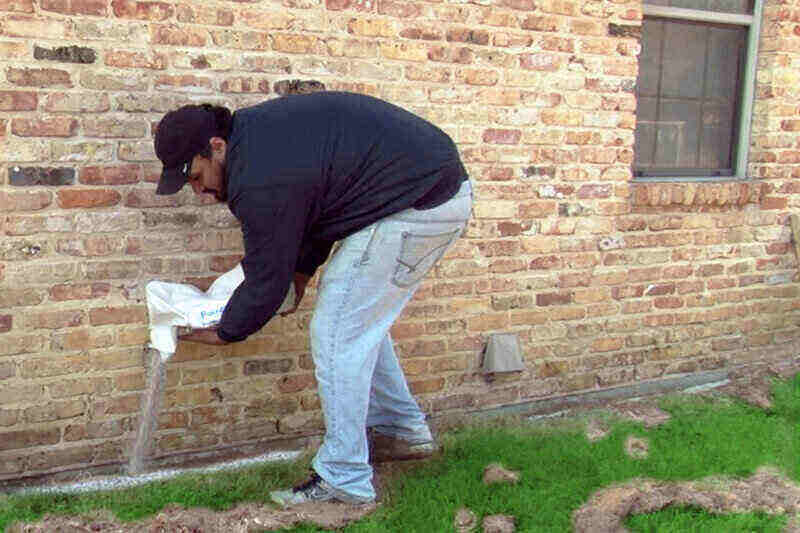 dělník pokládá termitovou bariéru podél domu