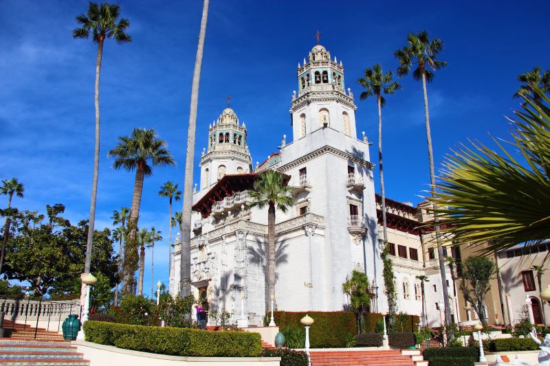 The front of Hearst Castle and its landscaped grounds on a clear, sunny day in San Simeon, California