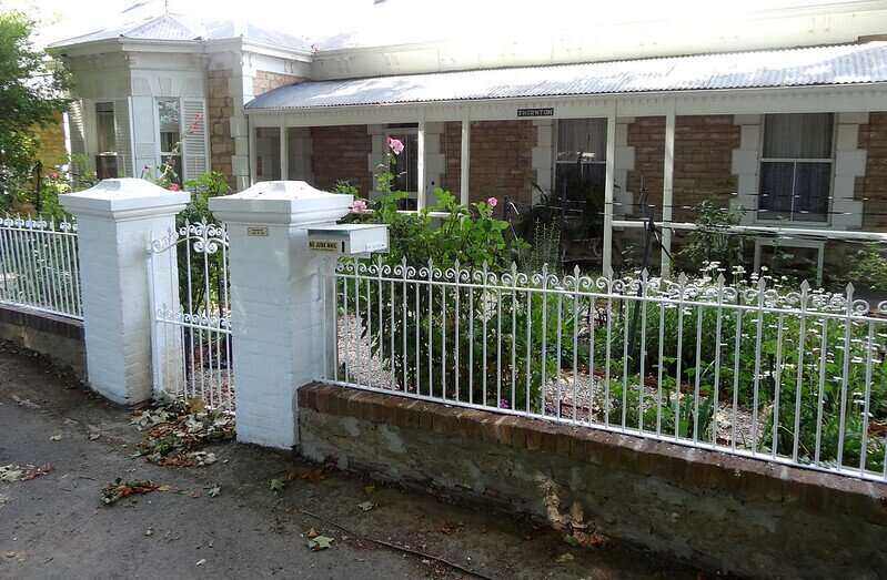 White wrought iron gate set on top of brick and between brick columns